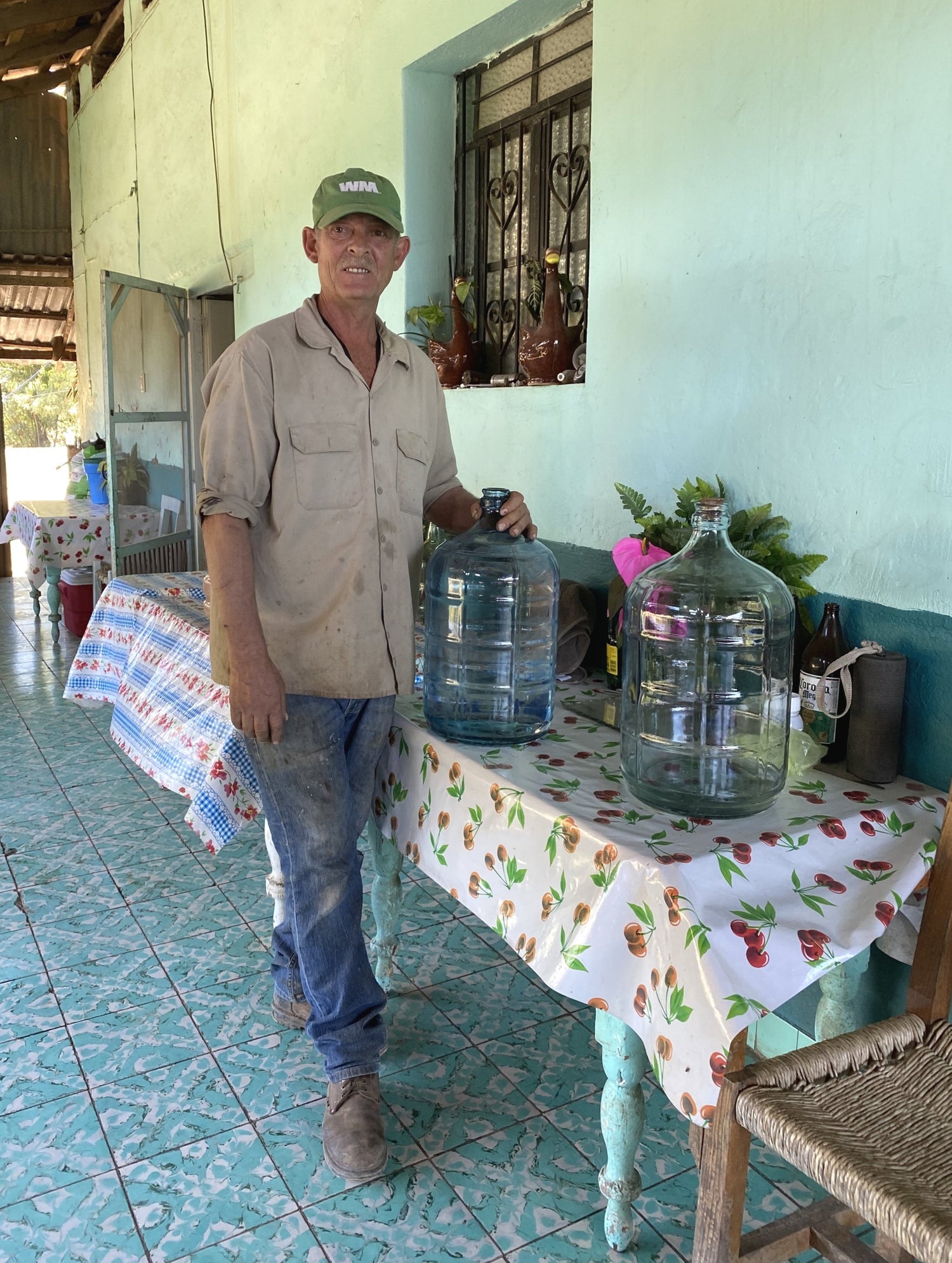 a man standing with large containers filled with mezcal ready for the bottling process
