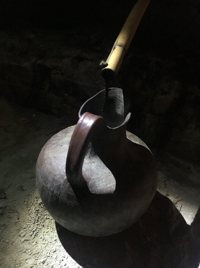 A small rope directs the dripping mezcal into the clay collection pot
