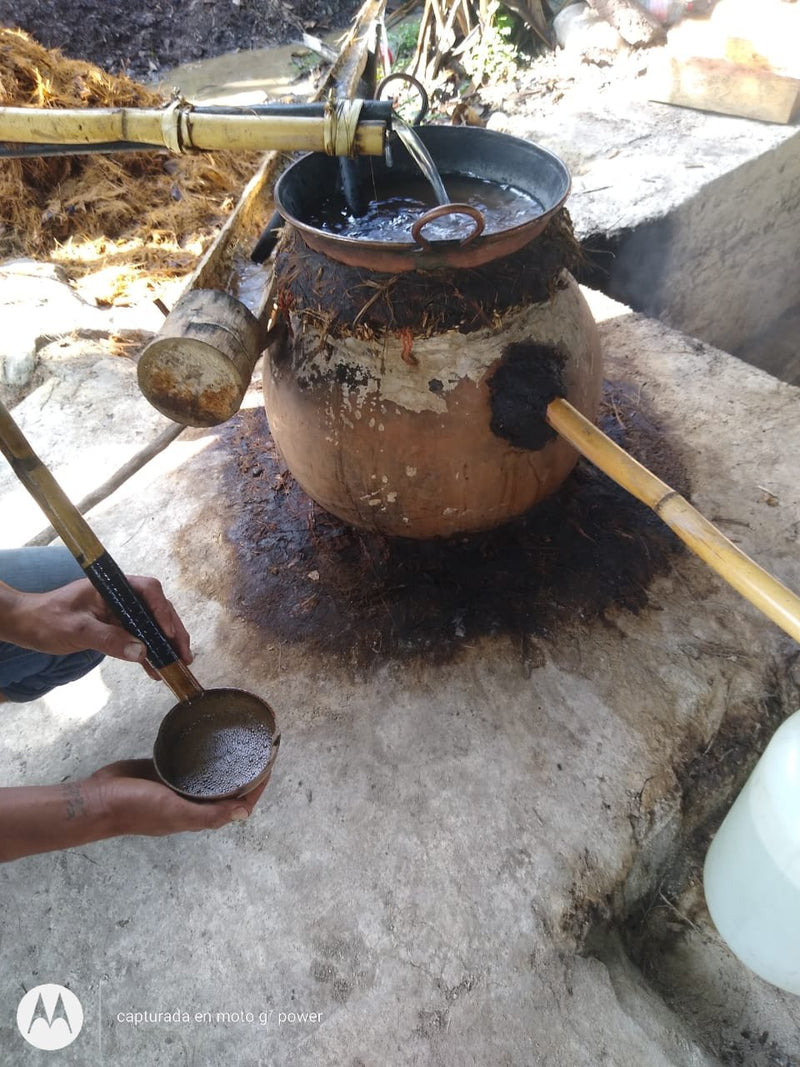 Sebastian checking the perlas of fresh mezcal running off the clay still