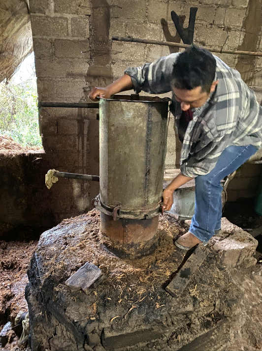 A man building a copper pot still for mezcal production
