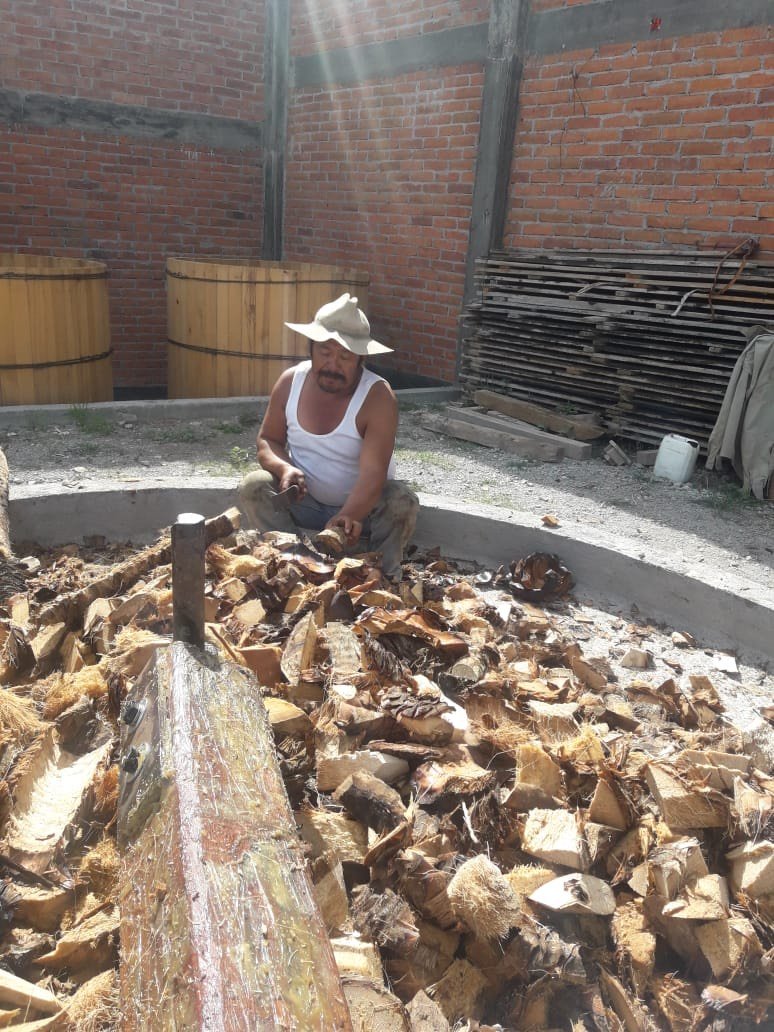 a man crushing pina's by hand to be used for making mezcal