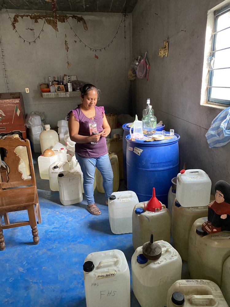 A woman with a pen surrounded by plastic containers full of mezcal