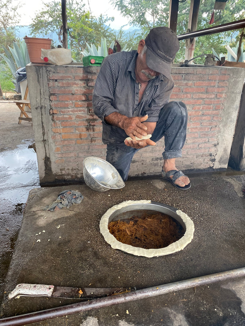 A man re-building a still for mezcal production with masa ‘cement’