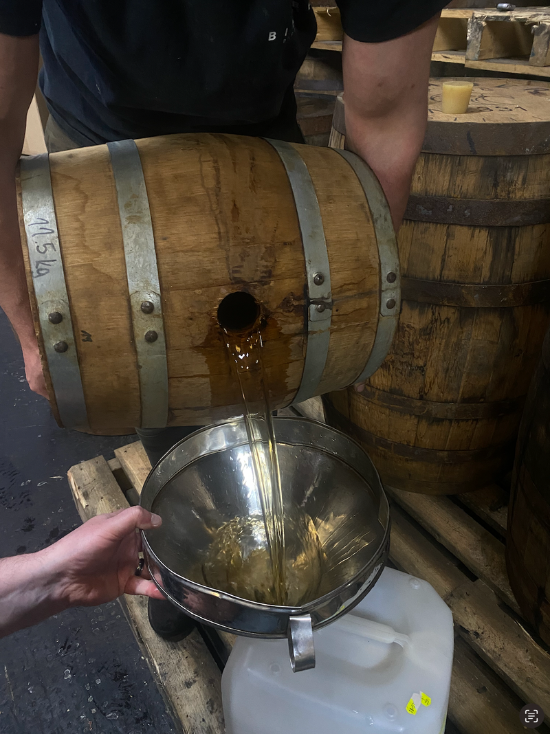 A barrel pouring mezcal into a funnel Finishing the ageing of this batch of mezcal
