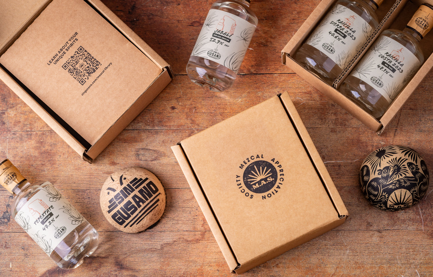 Bottles and packaging of the Mezcal Appreciation Society on a wooden surface